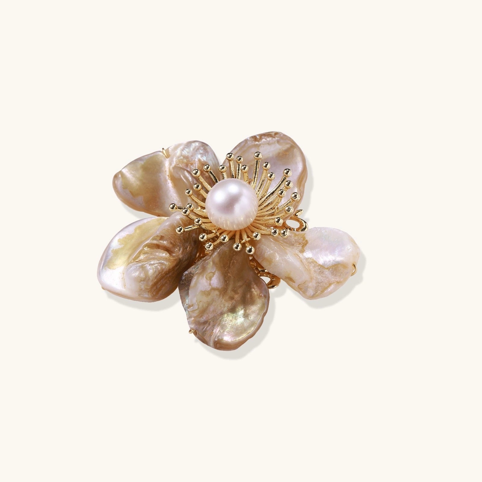Flower-shaped brooch with iridescent shell petals, freshwater pearl center, and gold-plated radiating details.
