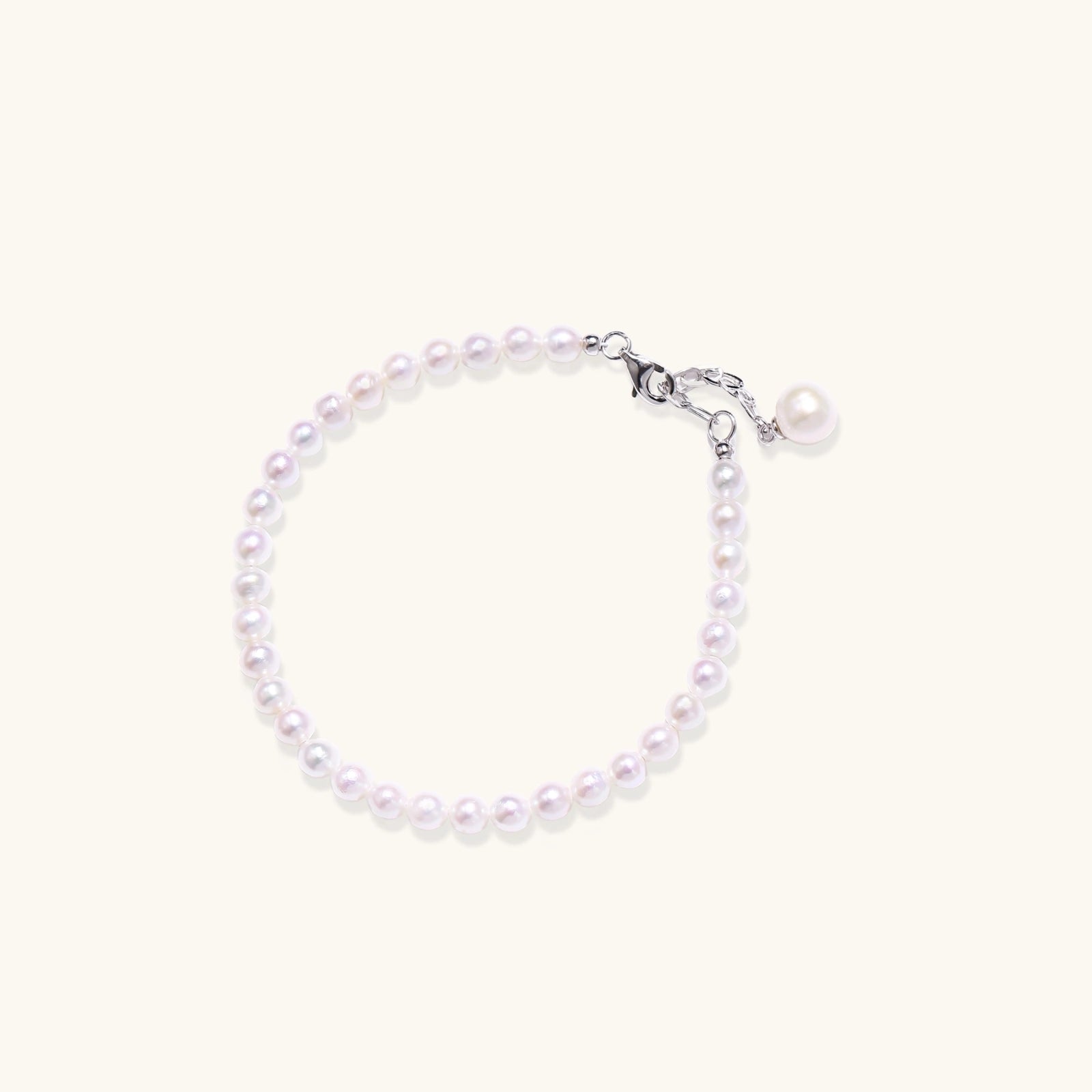 Adjustable bracelet featuring lustrous freshwater pearls with rhodium-plated sterling silver clasp on cream background.