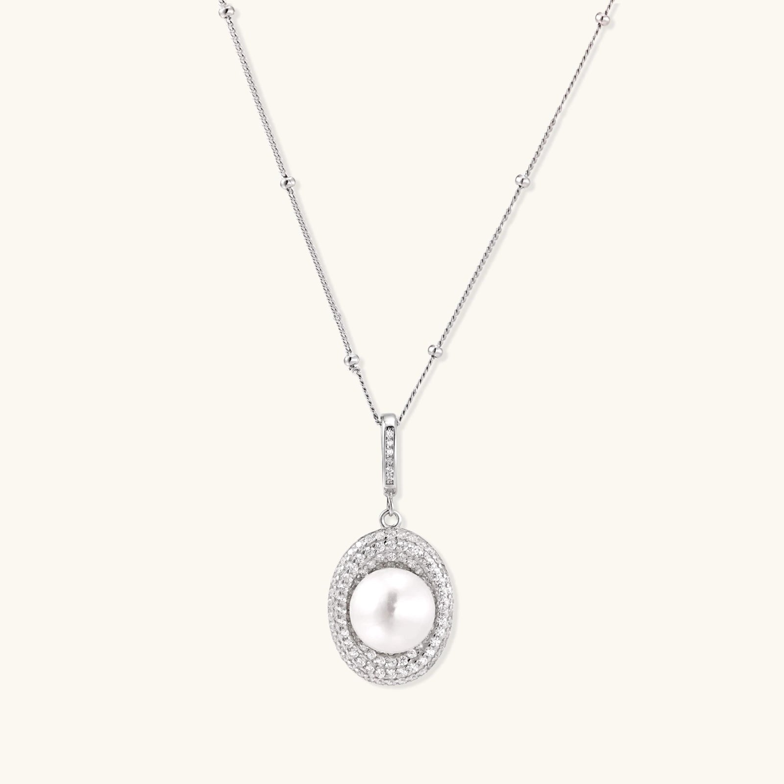 Oval sterling silver pendant with crystal halo surrounding a white freshwater pearl on delicate chain