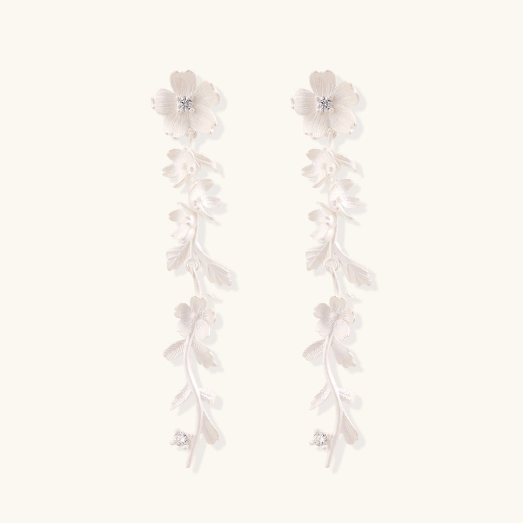 Long sterling silver drop earrings with delicate floral vine design and crystal accents on white background