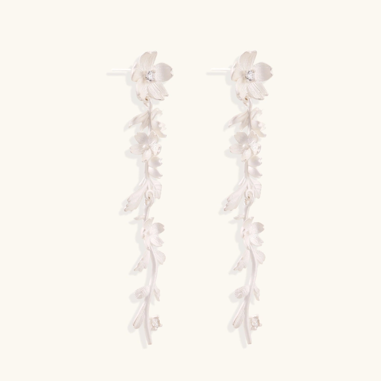 Long sterling silver drop earrings with delicate floral vine design and crystal accents on white background