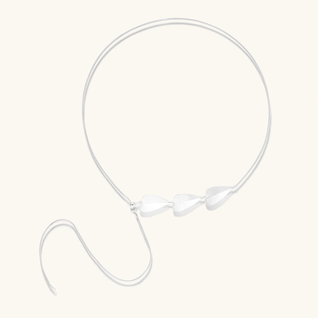 Minimalist sterling silver necklace with three brushed leaf-shaped pendants on delicate chain against white background