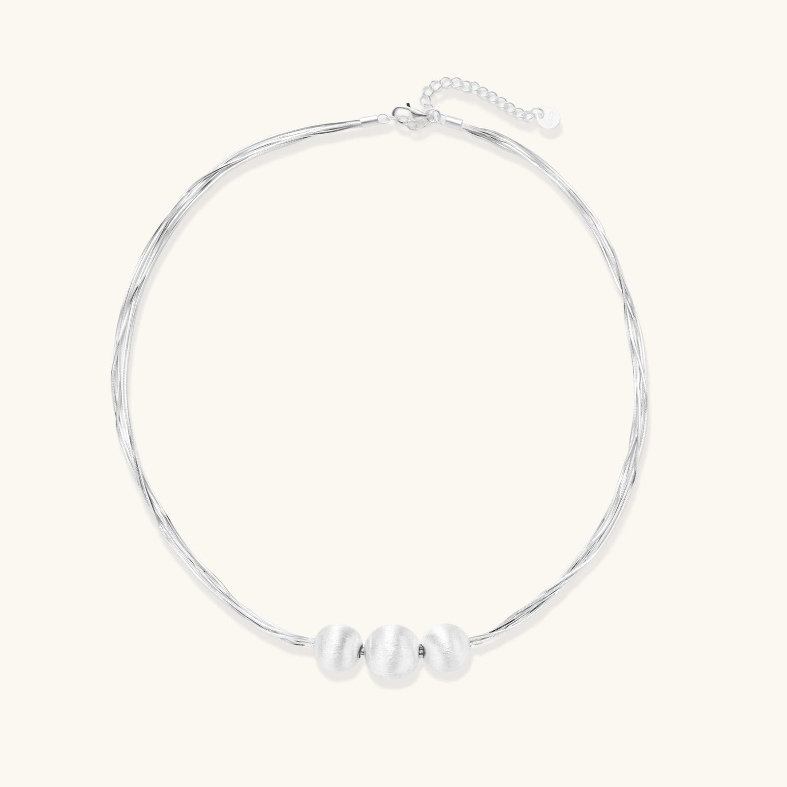 Sterling silver multi-strand necklace with three brushed round beads on cream background