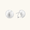 Brushed sterling silver half-dome clip-on earrings with textured surface against cream background