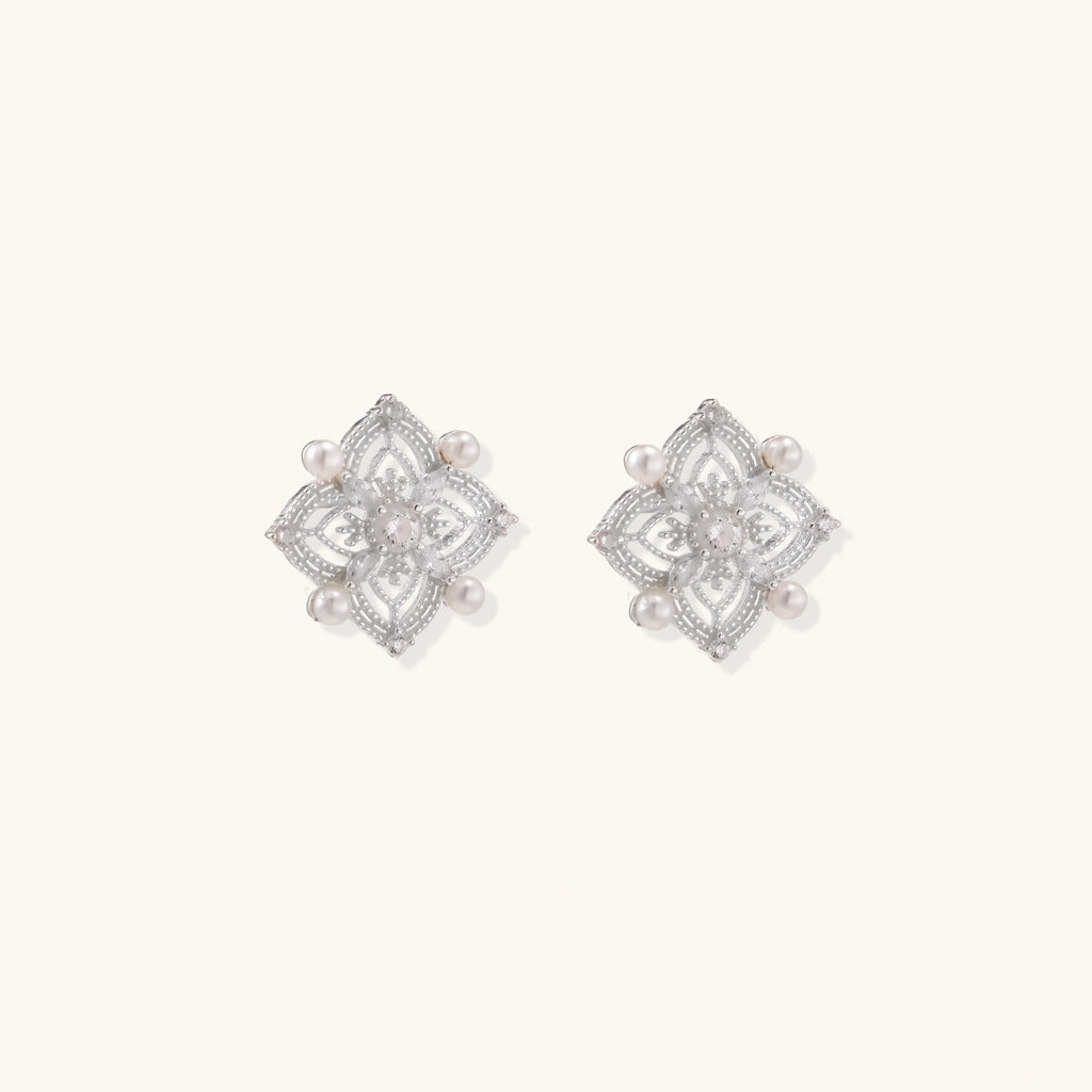 Ornate sterling silver stud earrings with mandala-inspired filigree pattern and four freshwater pearls on beige background