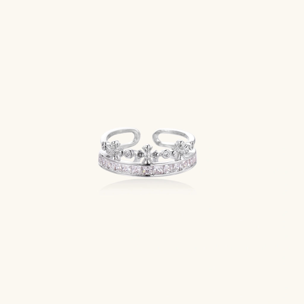 Silver-toned adjustable crown ring with channel-set square zirconia stones and delicate floral details on white background