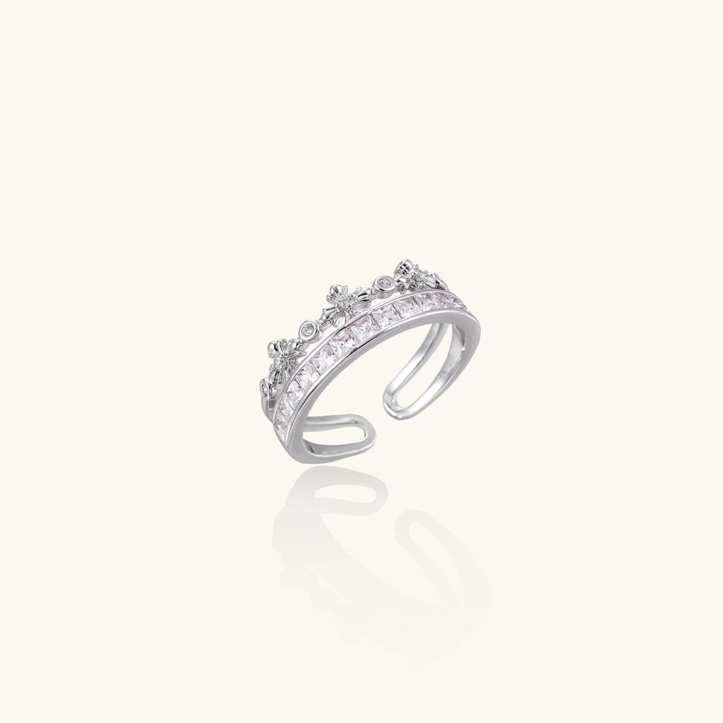 Silver-toned adjustable crown ring with channel-set square zirconia stones and delicate floral details on white background